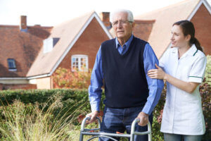 Nurse assisting man with walker